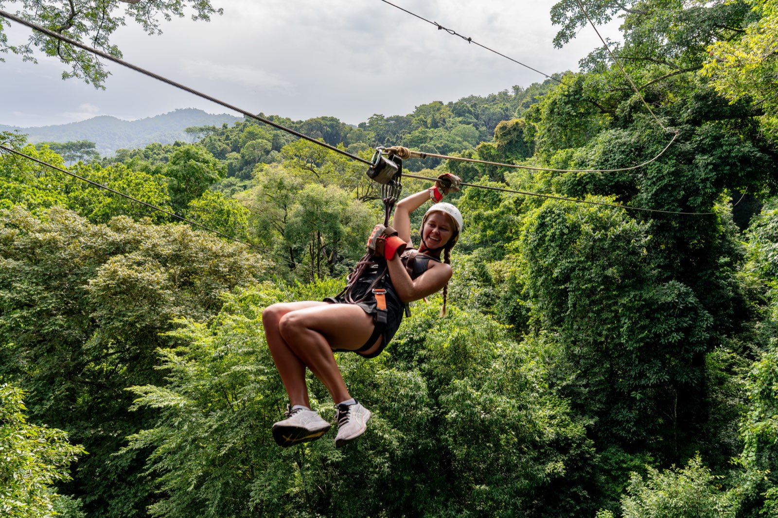 Guest ziplining over the rainforest with mountain canopy below